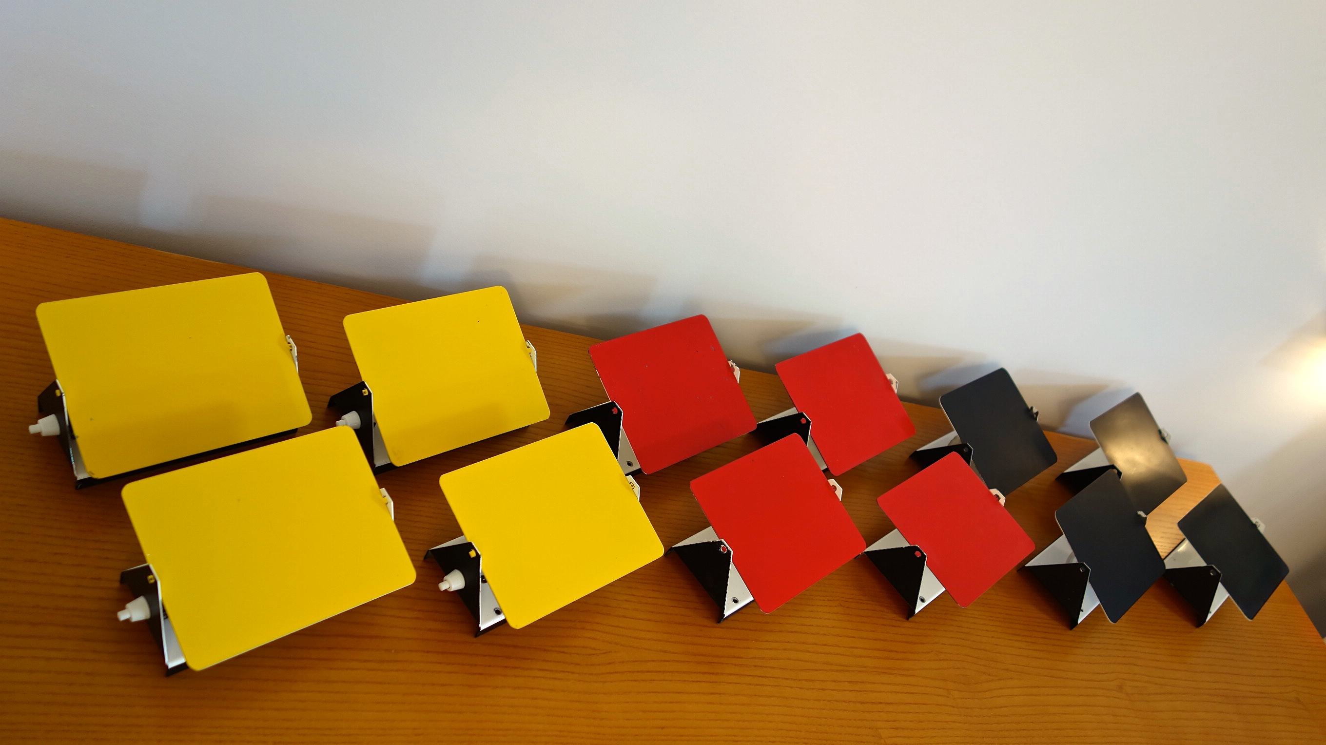 Charlotte PERRIAND (1903-1999) Ensemble de 6 appliques « CP1″ – 1962 Réflecteurs en métal laqué émaillé rouge, jaune et noir; base en métal blanc. Provenance station des Arcs, étiquette SCE, circa 1970. Ht: 12,5cm, l: 17cm p: 7cm